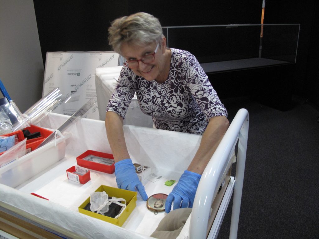Teresa Werstak, Conservator, preparing to install a portrait miniature of Governor Lachlan Macquarie and a daguerreotype in a showcase for the Australian Men’s Style display